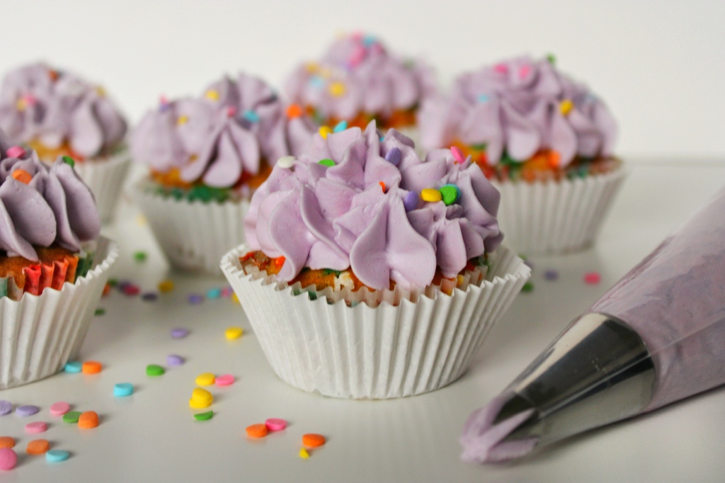confetti sprinkle cupcake with purple buttercream frosting piping bag